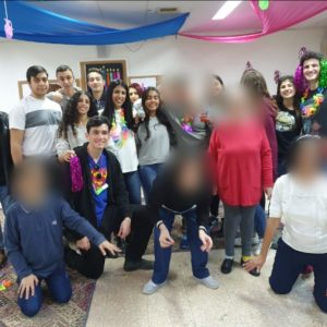 תלמידי אורט נעמי שמר בגן יבנה מדליקים נר חנוכה עם דיירי הוסטל בעלי צרכים מיוחדים